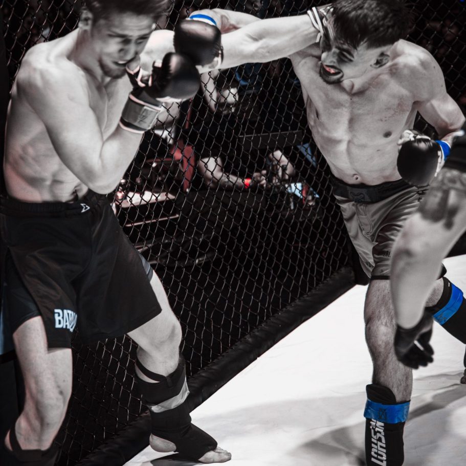 Armando Pascal Jukic Zwei Kämpfer im MMA-Ring, einer schlägt mit einem rechten Hook zu.